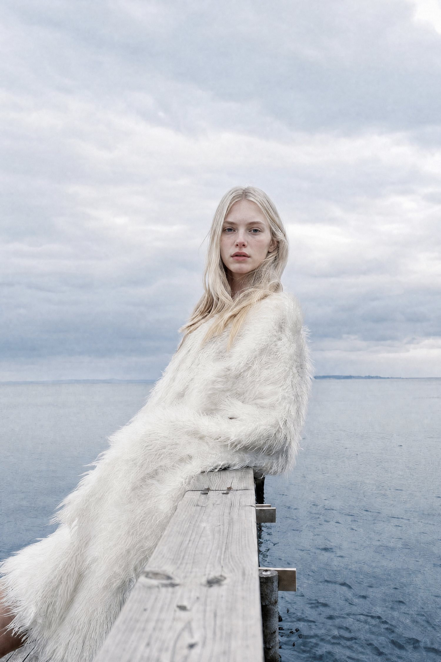 Memories of Scandinavia — model in white fur on a wooden pier by the sea